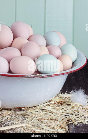 Antique wash pan filled with colorful fresh farm raised eggs against a rustic background. Stock Photo