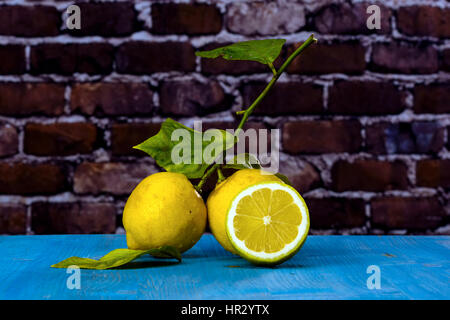 Two yellow lemons and leaf over a black wooden table blue. Stock Photo