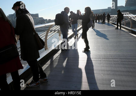 People enjoying a sunny winter day on the Millennium Bridge in London England UK  KATHY DEWITT