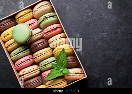 Colorful macaroons in a gift box on stone table. Sweet macarons. Top view with copy space Stock Photo