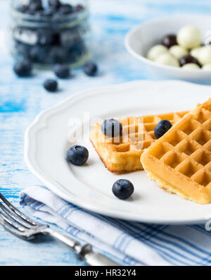 Belgian waffles on white plate on light blue background. Stock Photo