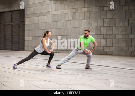 fitness, sport, exercising, training and people concept - couple doing triceps dip exercise on city street bench Stock Photo