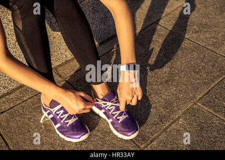 Running shoes. Barefoot running shoes closeup. Female athlete tying laces for jogging on road in minimalistic barefoot running shoes. Runner getting Stock Photo