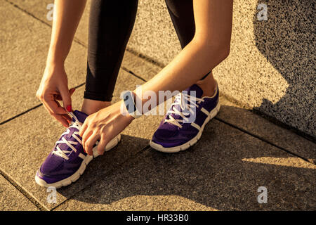 Running shoes. Barefoot running shoes closeup. Female athlete tying laces for jogging on road in minimalistic barefoot running shoes. Runner getting Stock Photo