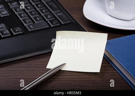 Note paper, pen, keyboard and cup of coffee on dark wooden office desk. Stock Photo