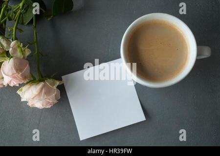 Light pink chinese rose with coffee and sticker on grey concrete background Stock Photo