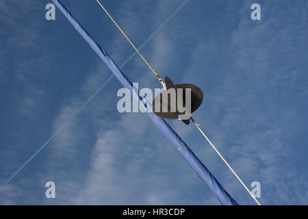 Anchor ball in yachts rigging with rolled foresail against a blue sky ...