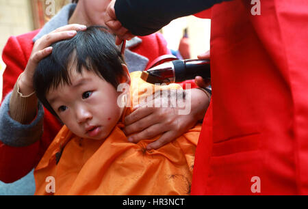 Hefei, Hefei, China. 27th Feb, 2017. Hefei, CHINA-February 27 2017: (EDITORIAL USE ONLY. CHINA OUT) .A barber cuts hair for a kid in Hefei, east China's Anhui Province, February 27th, 2017.It's Dragon Heads-raising Day on February 27th, 2017. Many Chinese people will hit the barbers' chair in search of good luck and prosperity on this day. Credit: SIPA Asia/ZUMA Wire/Alamy Live News Stock Photo