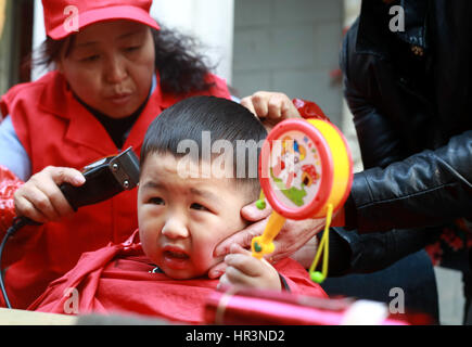Hefei, Hefei, China. 27th Feb, 2017. Hefei, CHINA-February 27 2017: (EDITORIAL USE ONLY. CHINA OUT) .A barber cuts hair for a kid in Hefei, east China's Anhui Province, February 27th, 2017.It's Dragon Heads-raising Day on February 27th, 2017. Many Chinese people will hit the barbers' chair in search of good luck and prosperity on this day. Credit: SIPA Asia/ZUMA Wire/Alamy Live News Stock Photo