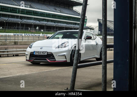 Front low angle of a white Nissan 370z Nismo on a race track, in pit lane. Stock Photo