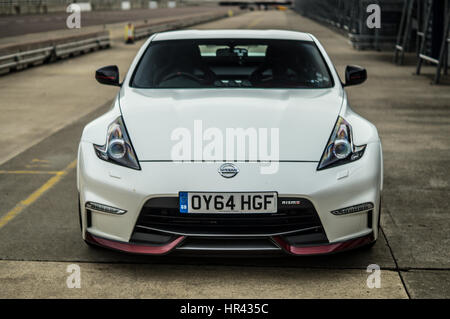 Front, head on shot of a white Nissan 370z Nismo on a race track, in pit lane. Stock Photo