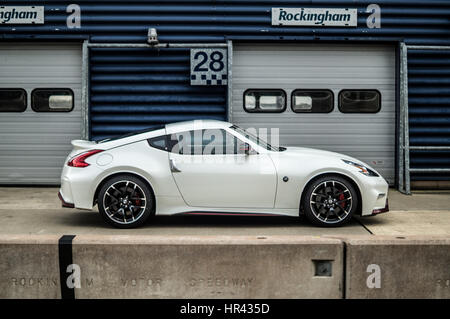 Side profile of a white Nissan 370z Nismo on a race track, in pit lane. Stock Photo