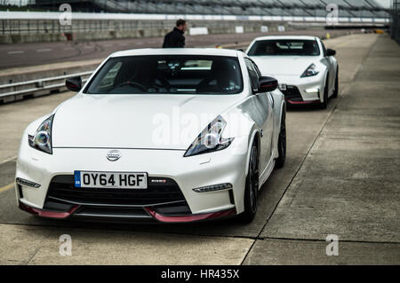 Two white Nissan 370z Nismo on a race track, in pit lane. Stock Photo