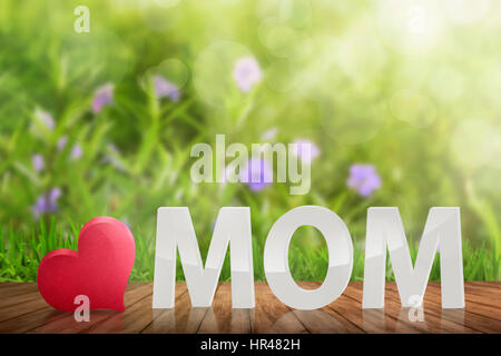 White 3D MOM text with red heart on the wooden table in garden Stock Photo