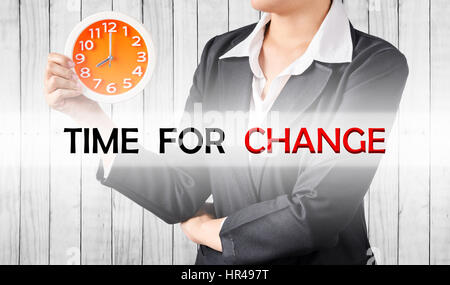 Time for change, and business woman holding clock on wood background. Business concept. Stock Photo