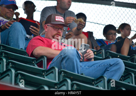 A man at a sporting event texting on his phone instead of watching the game. Stock Photo