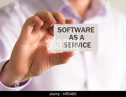 Closeup on businessman holding a card with SAAS SOFTWARE AS A SERVICE message, business concept image with soft focus background and vintage tone Stock Photo