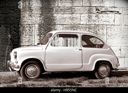 White old-timer super-mini car parked on grass against old wall in Pula, Croatia. Stock Photo