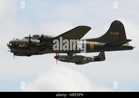 Boeing B17 Flying Fortress Sally B escorted by shark mouthed P51 Mustang fighter plane at the Flying Legends Air Show at IWM Duxford Stock Photo