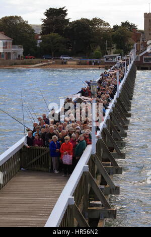 Faces in the crowd! People queueing patiently well wrapped up to board cruise pleasure steamer on Yarmouth Pier, Solent, Isle of Wight, UK Stock Photo