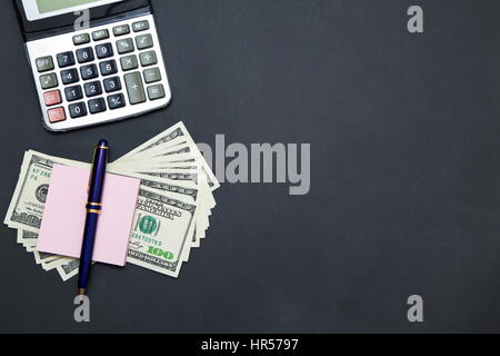US Dollars on black office table with calculator and notebook Stock Photo