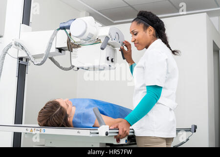 Young female doctor taking X-ray of woman lying on gurney in examination room Stock Photo