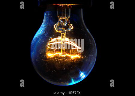 Old light bulb glowing in dark Stock Photo