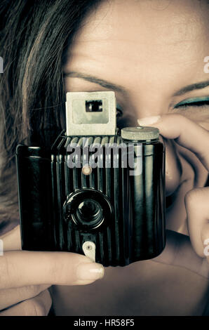 Female latina  photographer looking through the viewfinder of a vintage camera Stock Photo