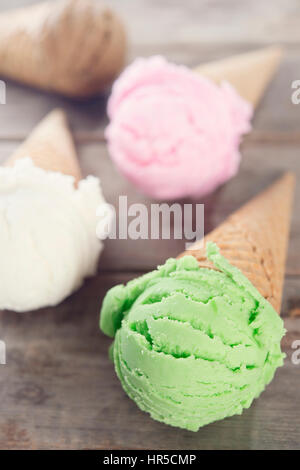 Different sorts of Ice Cream in a waffles on rustic wooden background. Stock Photo