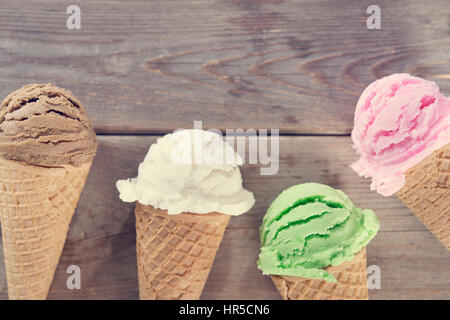 Chocolate, vanilla, matcha and strawberry ice cream in the cone on rustic wooden vintage background. Stock Photo