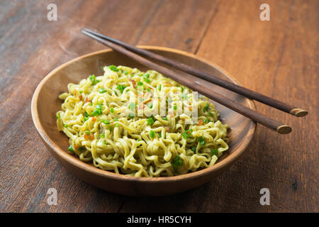 Cooked delicious Japanese ramen dried noodles with chopsticks on rustic wooden table, low light setting. Stock Photo