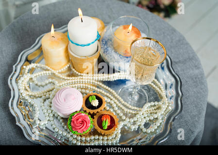 Candles, cake, pearls on a silver platter during the wedding. Stock Photo