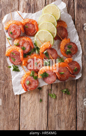 Grilled prawns with chorizo and herbs on skewers close-up on the table. vertical view from above Stock Photo
