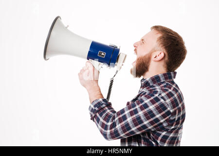 Young Bearded man in shirt screaming in megaphone in studio. Isolated white background Stock Photo