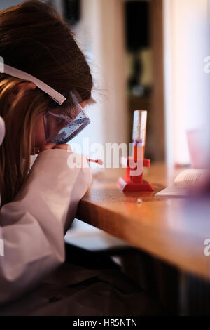 Young girl in white lab coat playing with chemistry science set Stock Photo