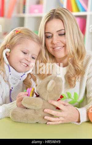 mother with little daughter playing with teddy bear, heeling it Stock Photo