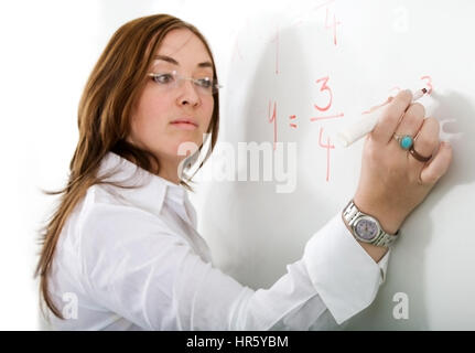 female teacher writing on a blackboard during a maths lesson - over a white background with the focus on her hand Stock Photo
