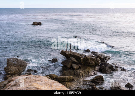Two young men taking cell phone photos by the ocean in Laguna Beach, California Stock Photo