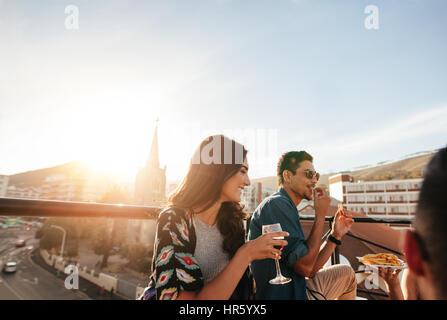 Young woman having drinks with friends. Group of friends partying on rooftop. Stock Photo