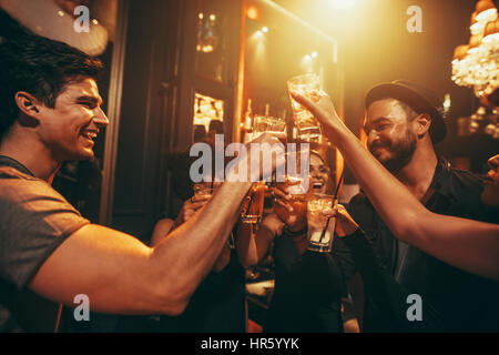 Young people celebrating and toasting drinks at nightclub. Friends having good time at club. Stock Photo