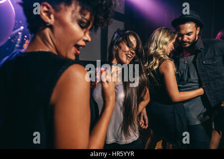 Group of young friends having fun together at the nightclub. Men and women dancing at disco. Stock Photo