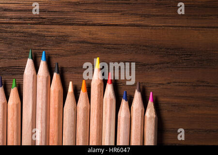 Background colored pencils lined up palette on wooden brown table. Top view. Vertical composition Stock Photo