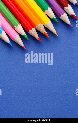 Colored pencils angle. Many different colored pencils on blue background Stock Photo