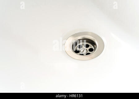 Small silver chrome metallic sink drain from a bath or sink with white ceramic copyspace area for bathroom based designs and themes. Stock Photo