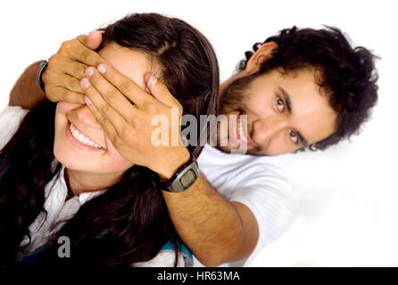 man covering a girls eyes to see if she can guess who is behind her - isolated over a white background Stock Photo