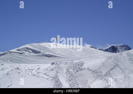 Snowboarder jumping in terrain park at ski resort on sun winter day. Caucasus Mountains, region Dombay. Stock Photo