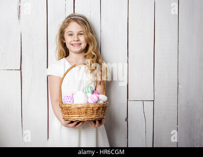 Little blonde girl holding basket with painted eggs. Easter day Stock Photo