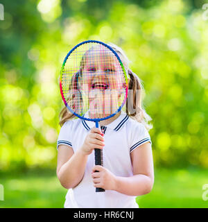 Active preschool girl playing badminton in outdoor court in summer. Kids play tennis. School sports for children. Racquet and shuttlecock sport for ch Stock Photo