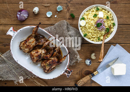 Delicious fried quails with eggs with bulgur porridge on a wooden table, rustic style. Top view. Stock Photo