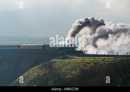 Puffing clouds of smoke, Locomotive, No. 60163 Tornado, a brand new Peppercorn A1 Pacific, travels across the Ribblehead Viaduct on a grey winter day. Stock Photo